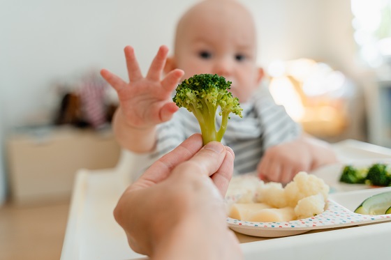 bebeluș mâncând broccoli